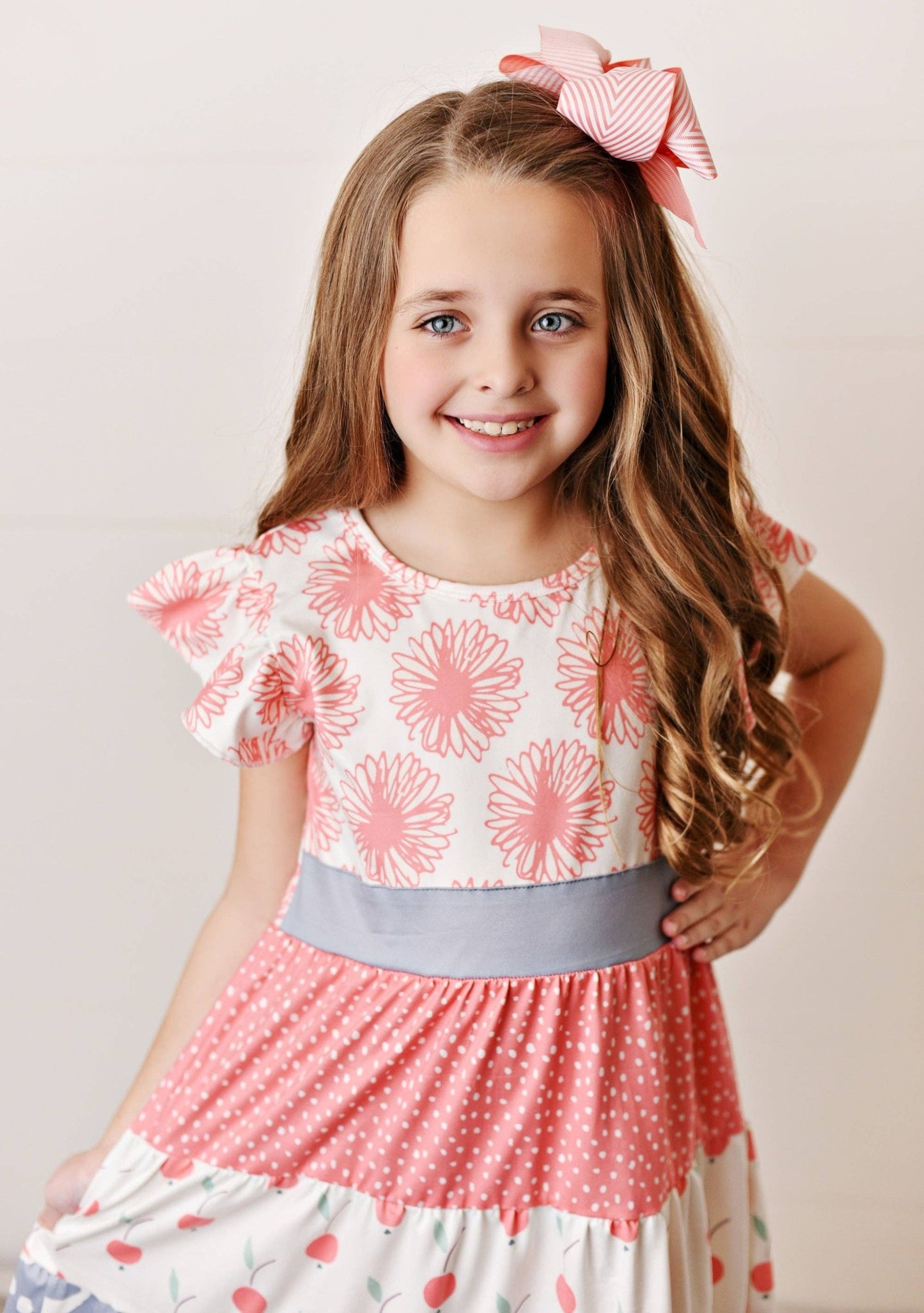 Perfect for the spring and summertime. The combination of the coral, flower, cherry, and dot print sounds so cheerful and fun. The tiered flutter sleeve adds a beautiful touch to the dress and is sure to make your little girl look and feel amazing!